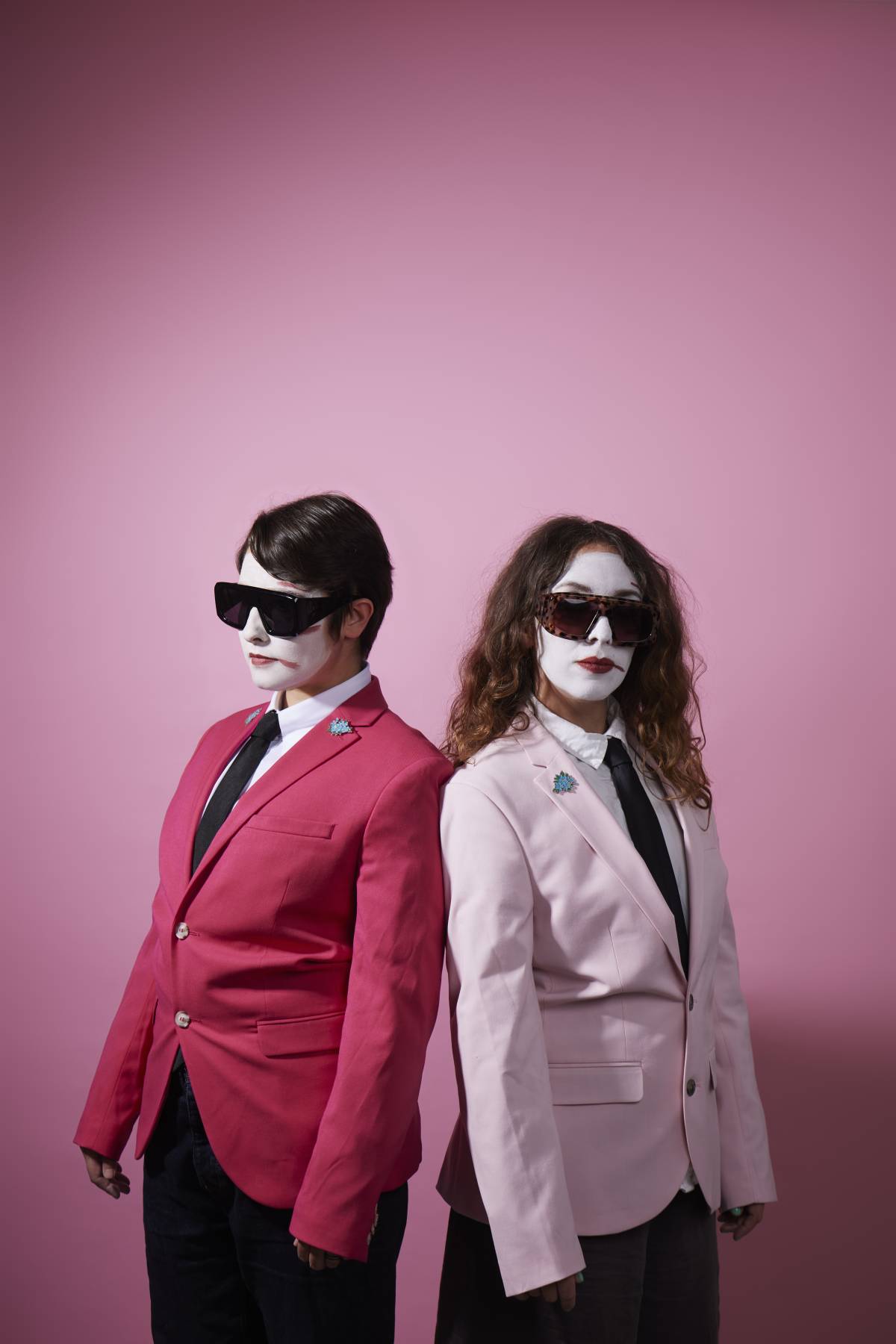 two women in white face paint, sunglasses and pink jackets