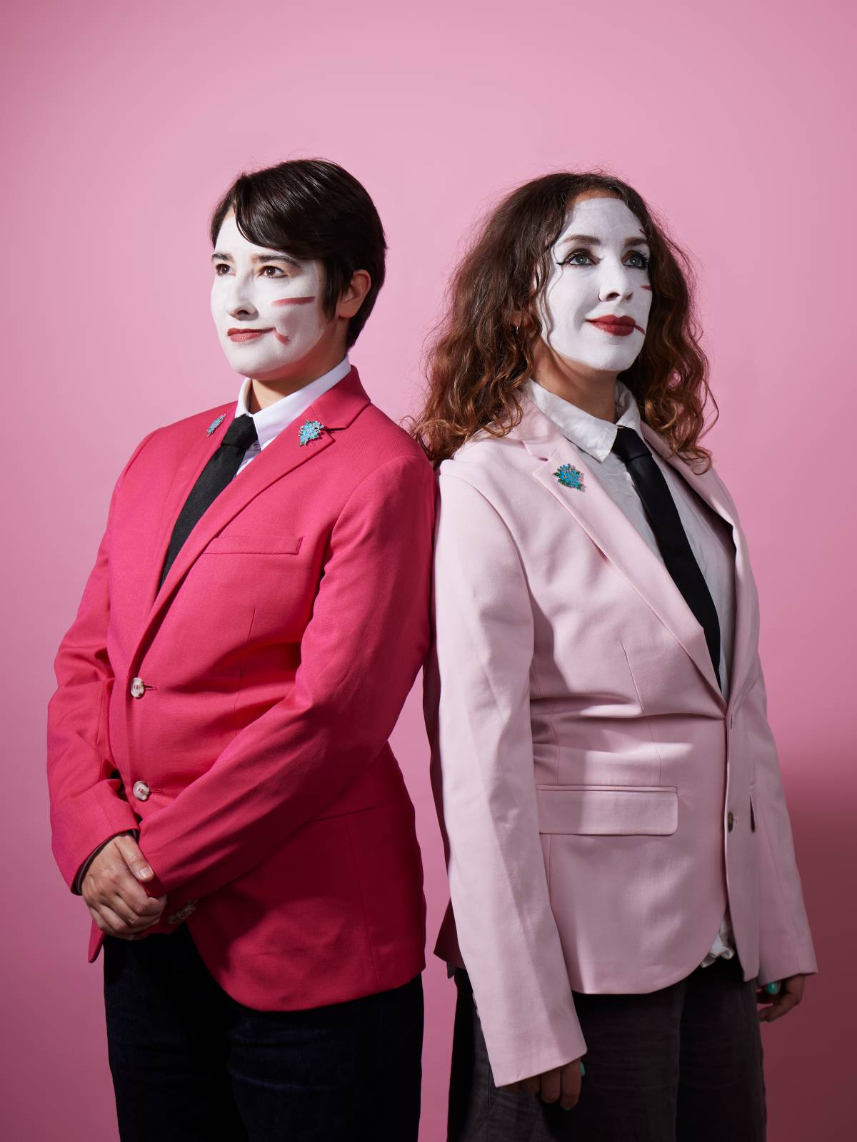 two performers in white face paint and pink jackets