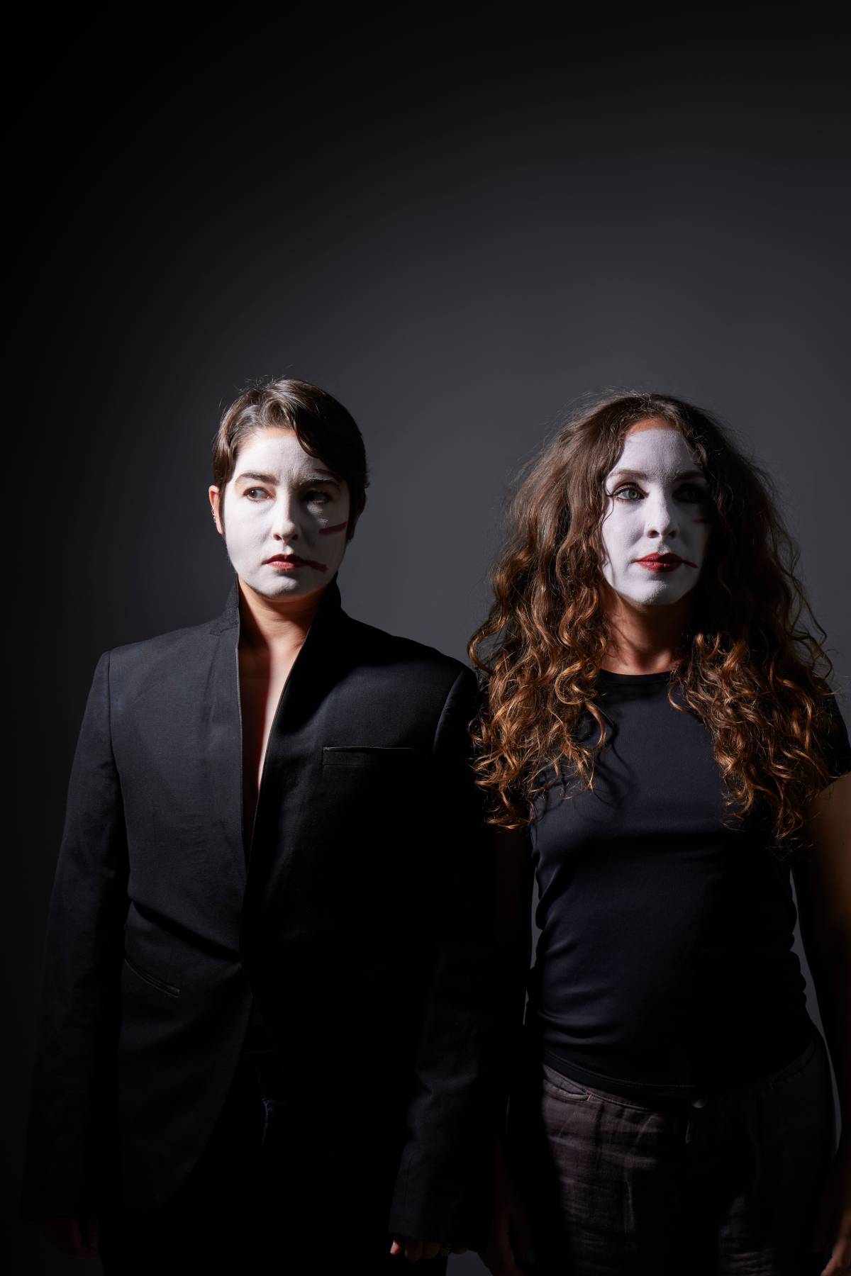 two women in white face paint and black suits